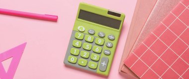 Pembe zemin üzerinde modern hesap makinesi ve kırtasiye malzemesi