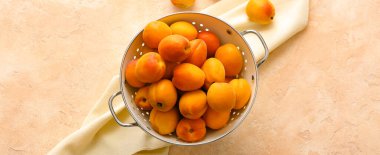 Renk arkaplanında lezzetli olgun kayısılara sahip Colander, üst görünüm