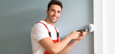 Teknisyen odaya akıllı ev güvenlik sistemi kuruyor