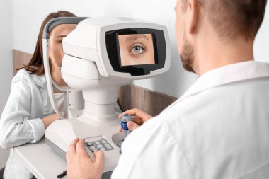 Oftalmolog modern klinikte genç bir kadını muayene ediyor.