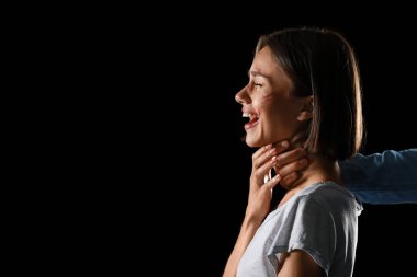 Siyah arka planda genç bir kadının boğazını sıkan adam. Şiddet kavramı
