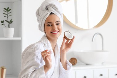 Banyoda şişesi ve hindistan cevizi olan genç bir kadın.