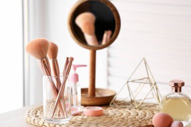 Pencerenin yanındaki masada makyaj fırçası olan cam tutucu, yakın plan.