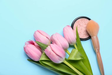Güzel pembe lalelerden bir buket, mavi arka planda allık ve fırça.