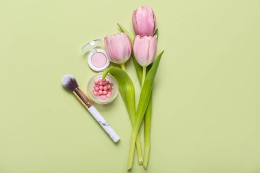 Kozmetik ürünleri ve yeşil arka planda lalelerle makyaj fırçası. Anneler Günü kutlaması
