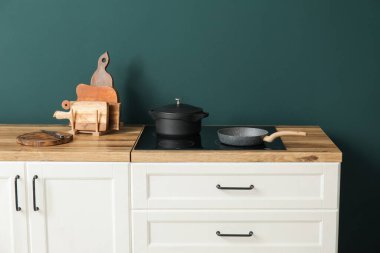 Kesme tahtaları, tencere, tava ve fırın yeşil duvarın yanında.