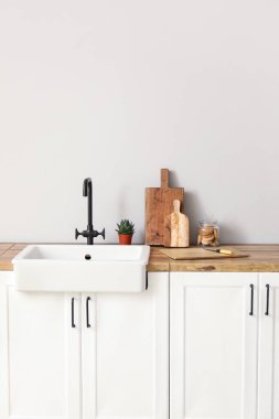 Işık duvarının yanındaki tezgahlarda kurabiye kavanozu, lavabo ve bitki kesme tahtaları.