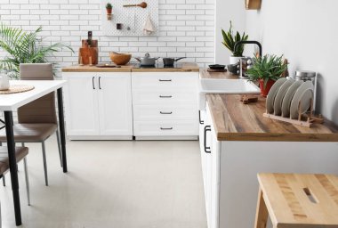 Mutfağın içinde yemek masası, tezgah ve çatal bıçak var.