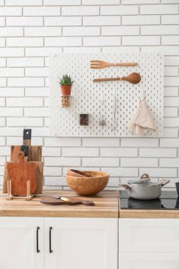 Beyaz tuğla duvarın yanındaki tezgahta bıçak ve kâse ile tahta kesme.