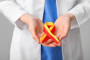 Gri arka planda farkındalık kurdelesi olan kadın doktor, yakın plan. Hepatit konsepti