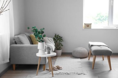 Yumuşak bank, kanepe ve çiçeklerle aydınlık oturma odasının içinde.