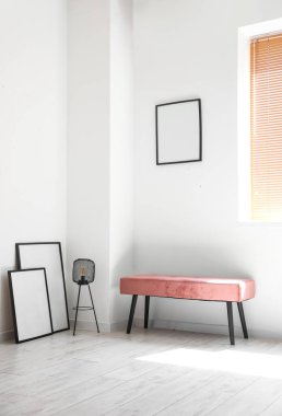 Lambalı pembe bank ve aydınlık odada boş çerçeveler.