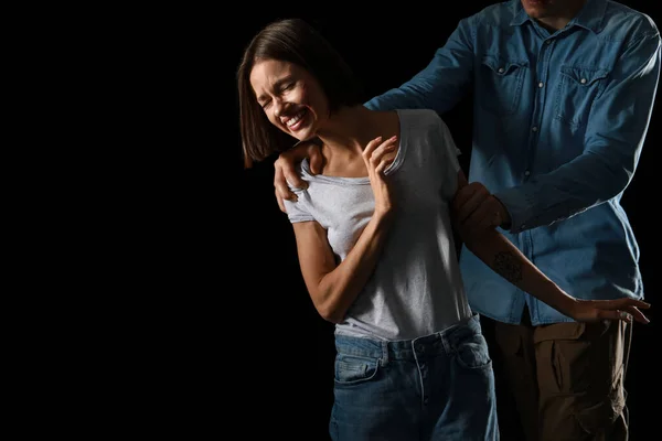 Man beating scared woman on dark background. Violence concept