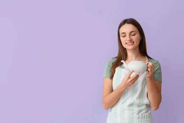 Hübsche Junge Frau Schürze Mit Teekanne Auf Lila Hintergrund — Stockfoto