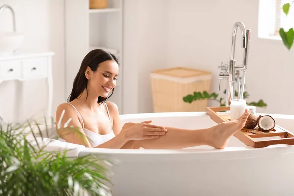 Schöne Frau Die Badezimmer Kokosöl Auf Ihr Bein Aufträgt — Stockfoto