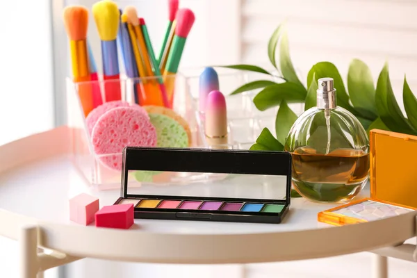 Cosmetic products with plant branch on table in room