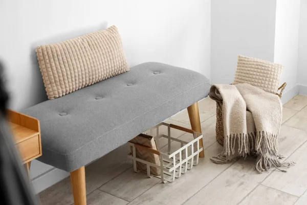 Soft bench with cushion and baskets near light wall