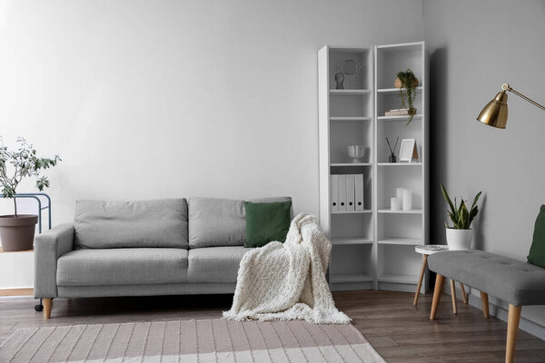 Interior of light living room with soft bench, sofa and shelving unit