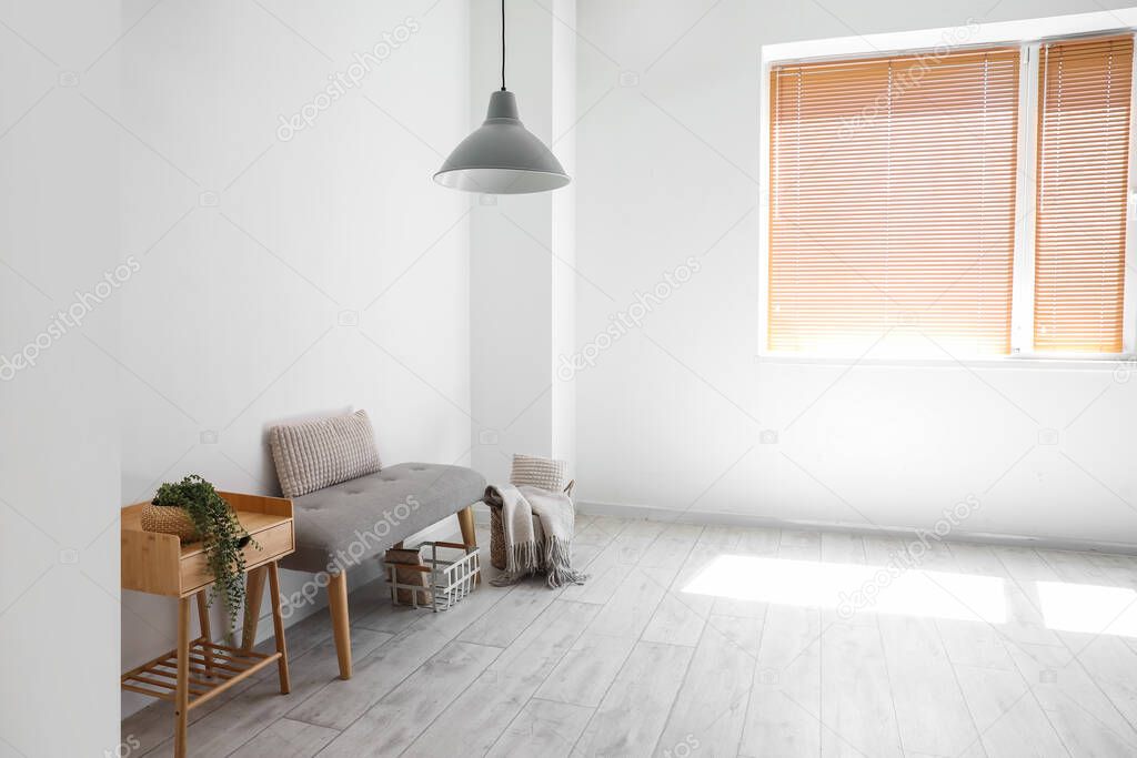 Soft bench with baskets and table near light wall