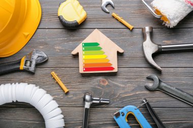 Ahşap arka planda inşaat malzemeleri ve enerji verimliliği derecesi olan ev modeli