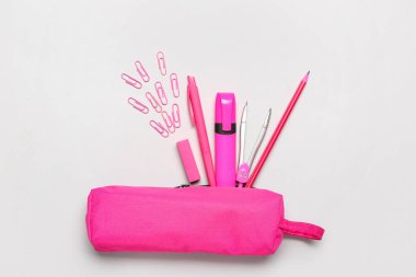 Kağıt raptiyeli pembe kalem kutusu ve arka planda kırtasiye malzemesi