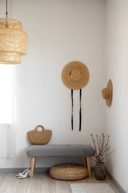 Çantalı yumuşak bank, vazoda ağaç dalları, puf ve ışıklı duvarın yanındaki ayakkabılar.