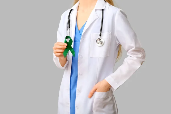 带着绿色带子和灰色背景听诊器的女医生 肝癌的概念 — 图库照片