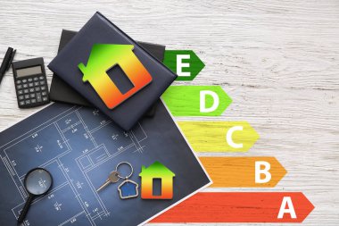 Evlerin, anahtarların, hesap makinelerinin çizimlerinin ve hafif ahşap arka planda not defterlerinin olduğu büyüteçlerin olduğu çizimler. Enerji verimliliği kavramı