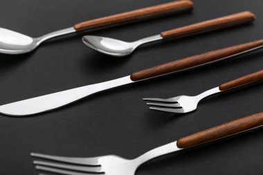 Siyah arka planda ahşap saplı paslanmaz çelik çatal bıçak seti.