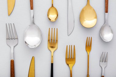 Işıklı arka planda farklı paslanmaz çelik çatal bıçak takımı, yakın plan.