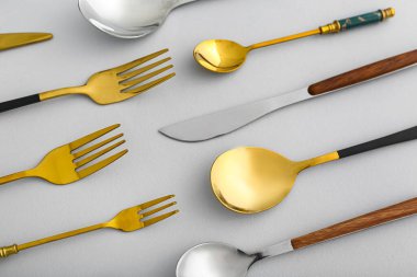 Işıklı arka planda farklı paslanmaz çelik çatal bıçak takımı, yakın plan.