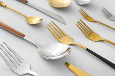 Işıklı arka planda farklı paslanmaz çelik çatal bıçak takımı, yakın plan.