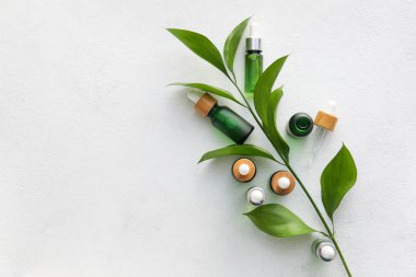 Işık arka planında doğal serum ve bitki yaprakları şişeleri