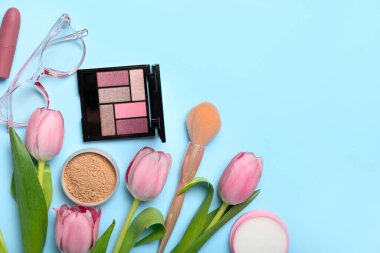 Güzel pembe laleler, dekoratif kozmetik ürünler ve mavi arka planda gözlük.