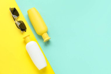 Arka planda güneş kremi ve güneş gözlüğü şişeleri