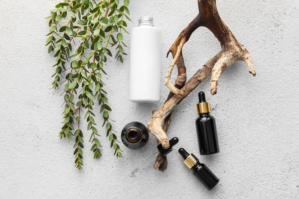 Doğal serum şişeleri, ağaç dalı ve bitki yaprakları.