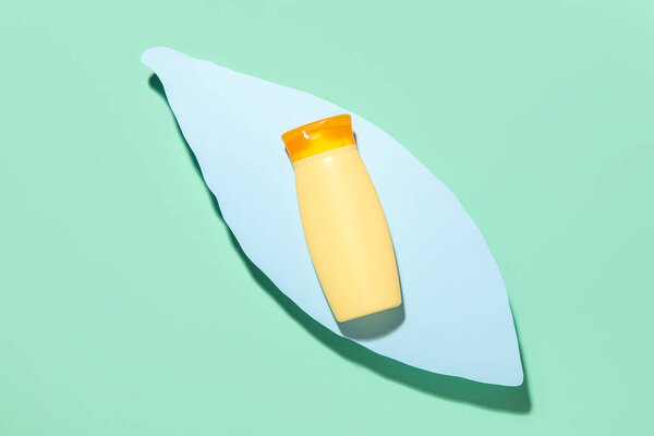 Крем для загара и декоративный пальмовый лист на цветном фоне