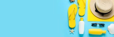 Açık mavi arkaplanda yazı için yeri olan güneş kremi ve plaj aksesuarları, üst görünüm