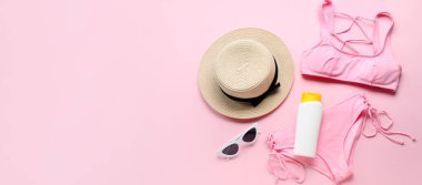 Pembe arkaplandaki mayo ve plaj aksesuarları metin için yer açıyor.