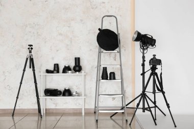 Modern fotoğraf stüdyosunda ışıklandırma ekipmanları, kamera, tripod ve siklonama.