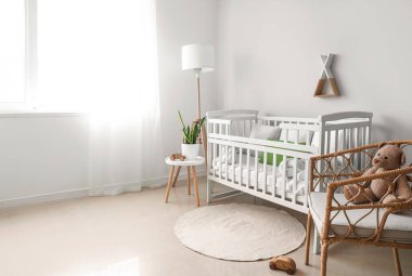 Bebek beşiği, lamba, masa ve koltuğu olan ışık odasının içinde.