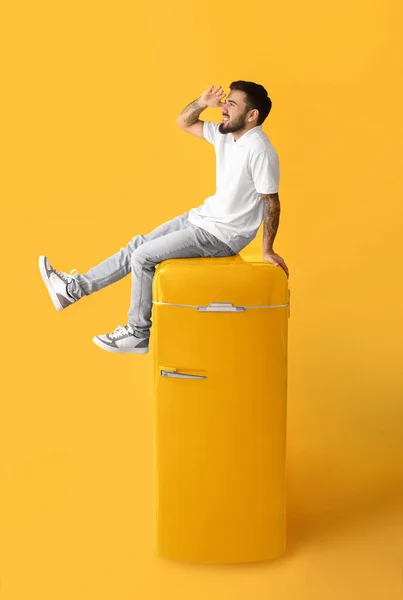 Cooler Tätowierter Junger Mann Sitzt Auf Gelbem Kühlschrank Vor Farbigem — Stockfoto
