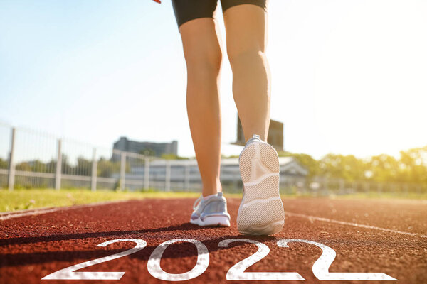 Sporty young woman running at the stadium. Concept of 2022 goals
