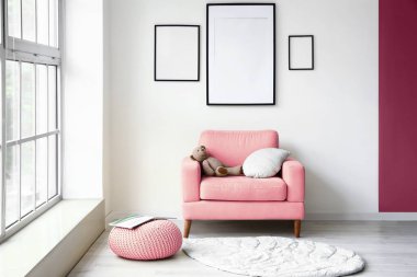 Pembe koltuklu, şezlonglu ve boş çerçeveli modern tarz bir oda.