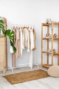 Kadın kıyafetleri ve ayakkabılarıyla aydınlık soyunma odasının içinde.