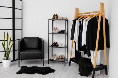 Kadın kıyafetleri, ayakkabıları ve koltuğu olan şık bir soyunma odası.