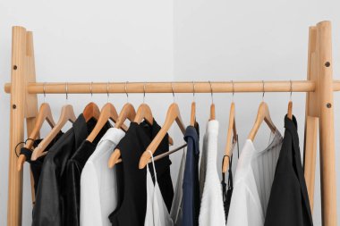 Ahşap askı ve ışık duvarının yanında kadın giysileri.