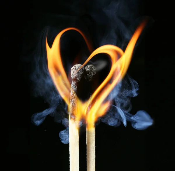 两个燃烧的火柴 在黑暗的背景下 火焰的形状 心的形状 — 图库照片