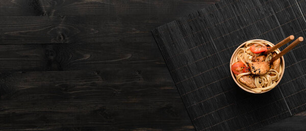 Бумажная чаша с вкусной китайской лапшой и мясом на темном деревянном фоне с местом для текста