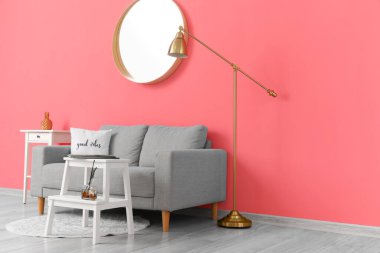 Rahat bir kanepe ve pembe duvarın yanında modern bir lamba.
